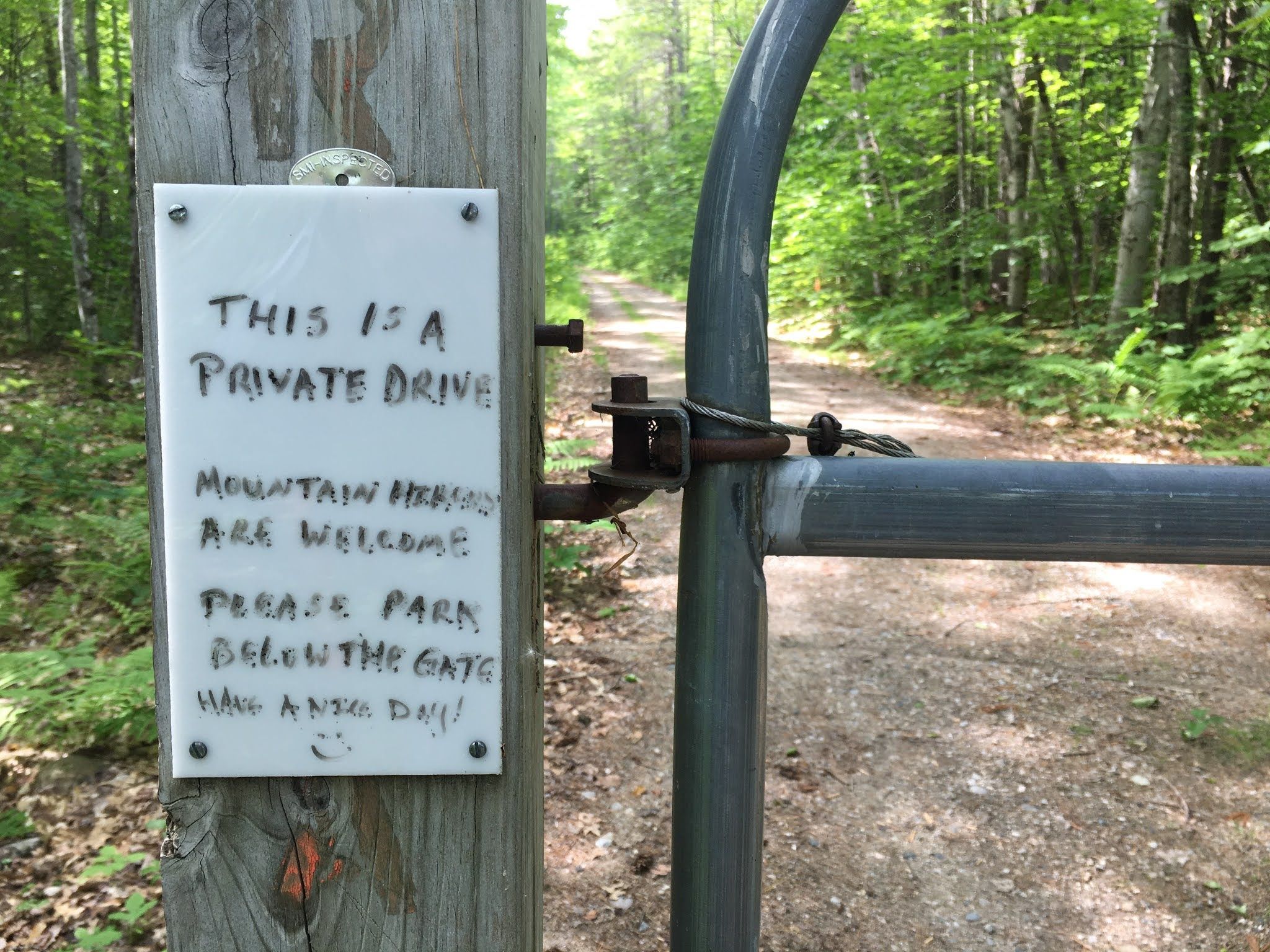 Sign on a road gate says: This is a private drive. Mountain hikers are welcome. Please park below the gate. Have a nice day.